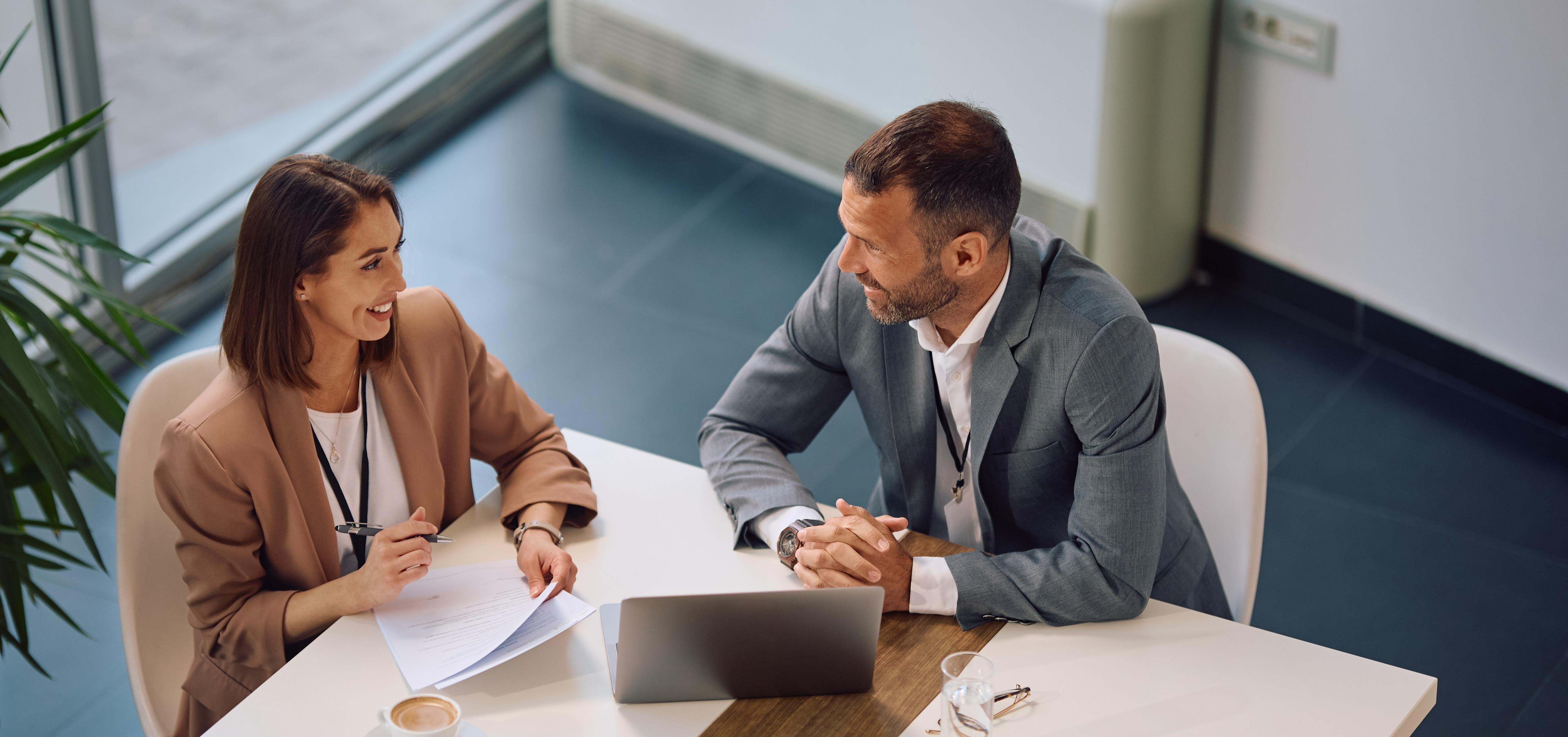 Poslovna žena i muškarac sastaju se za stolom, raspravljaju o partnerstvu.