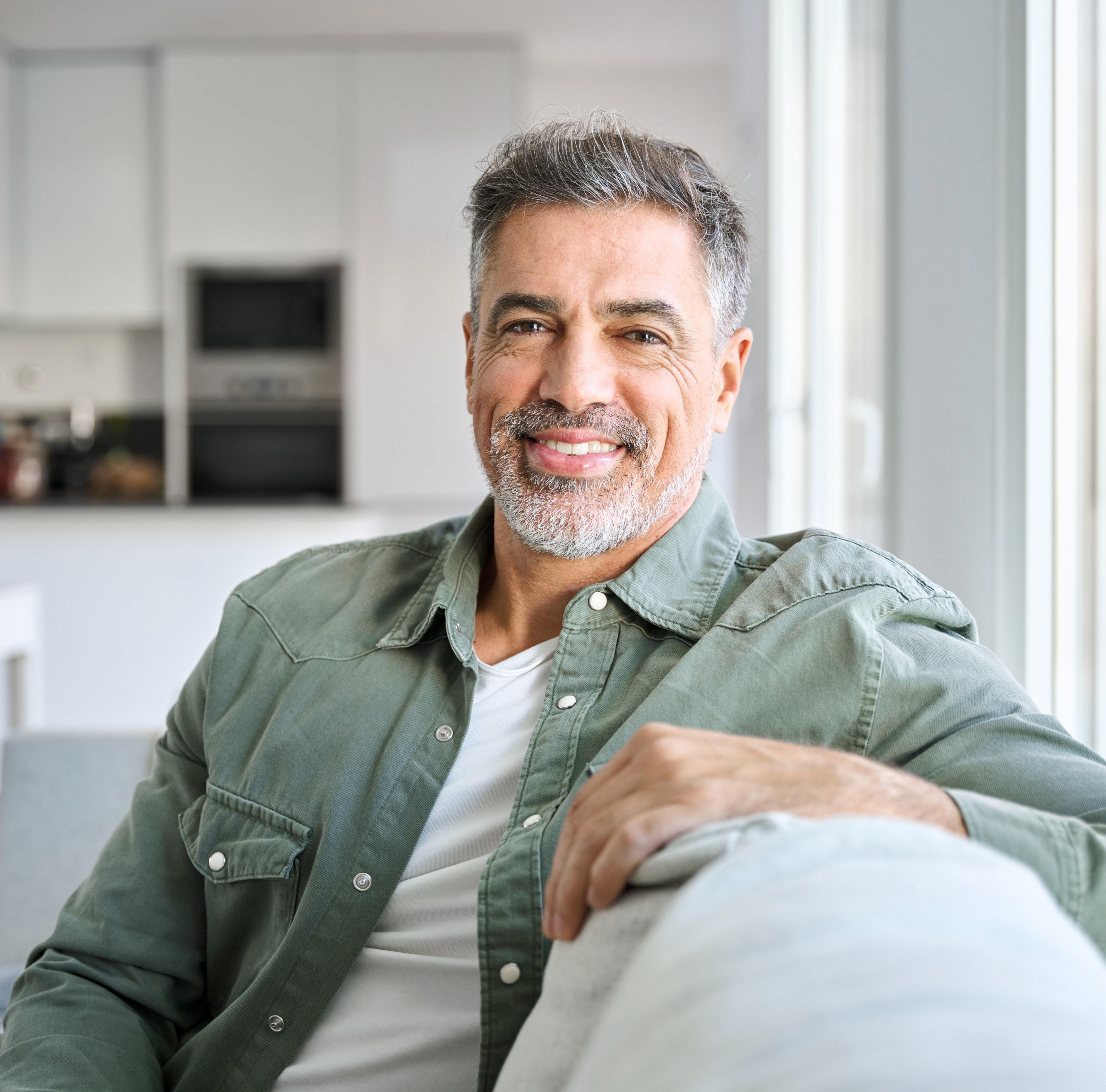 Glad husägare som slappnar av i en soffa i ett ljust vardagsrum.