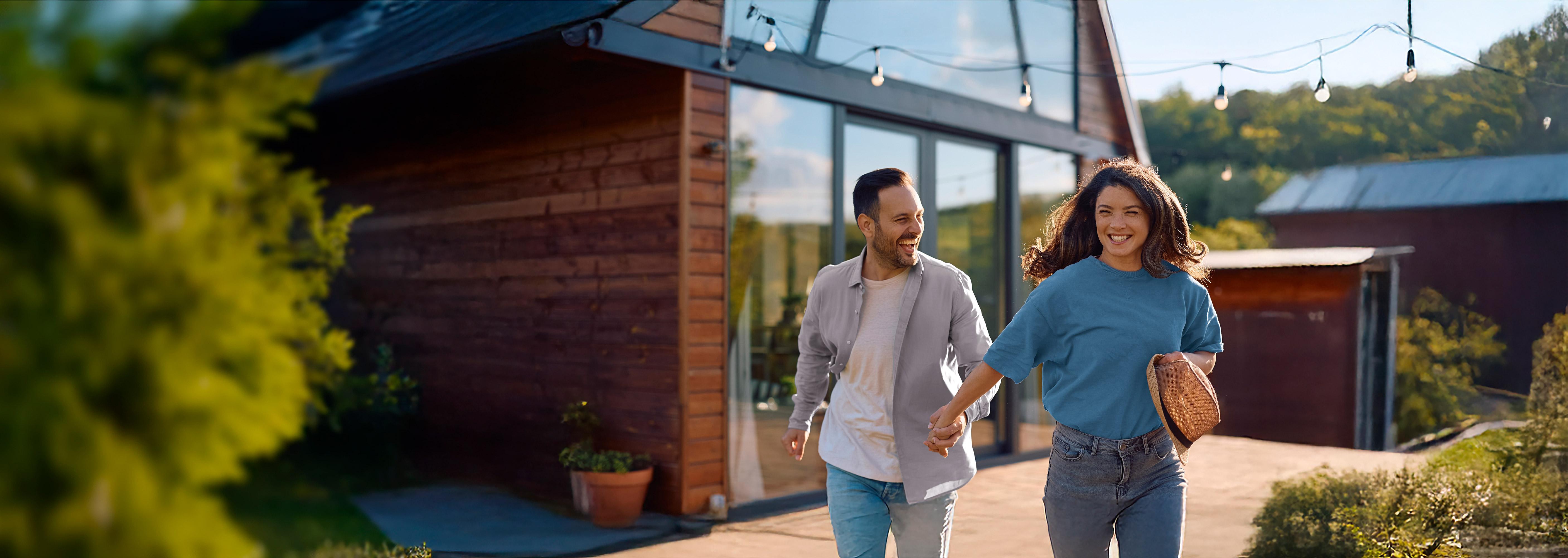Smilende par som går utenfor en moderne feriebolig.