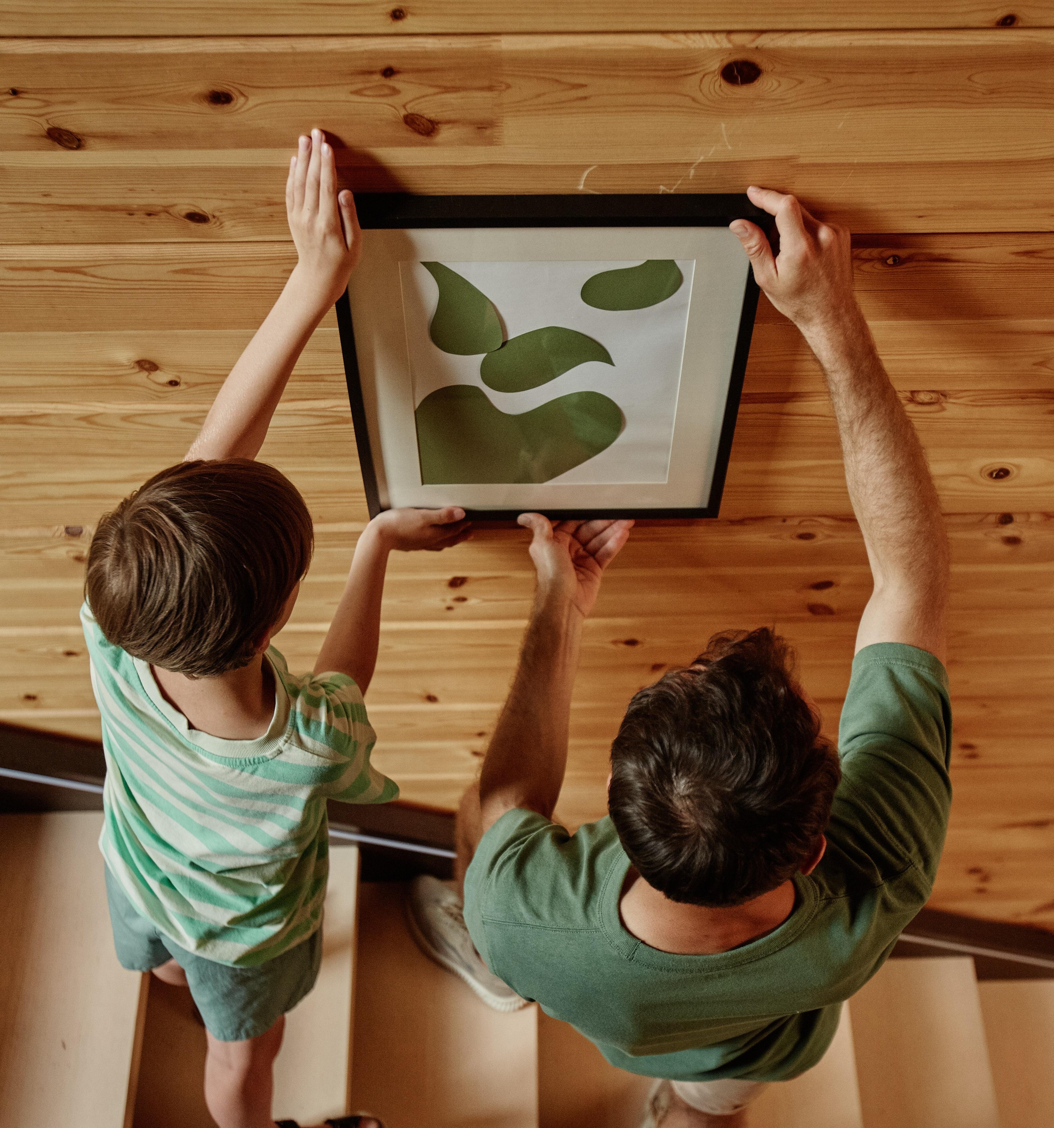Un padre y un hijo cuelgan un cuadro, lo que enfatiza la protección de su casa.