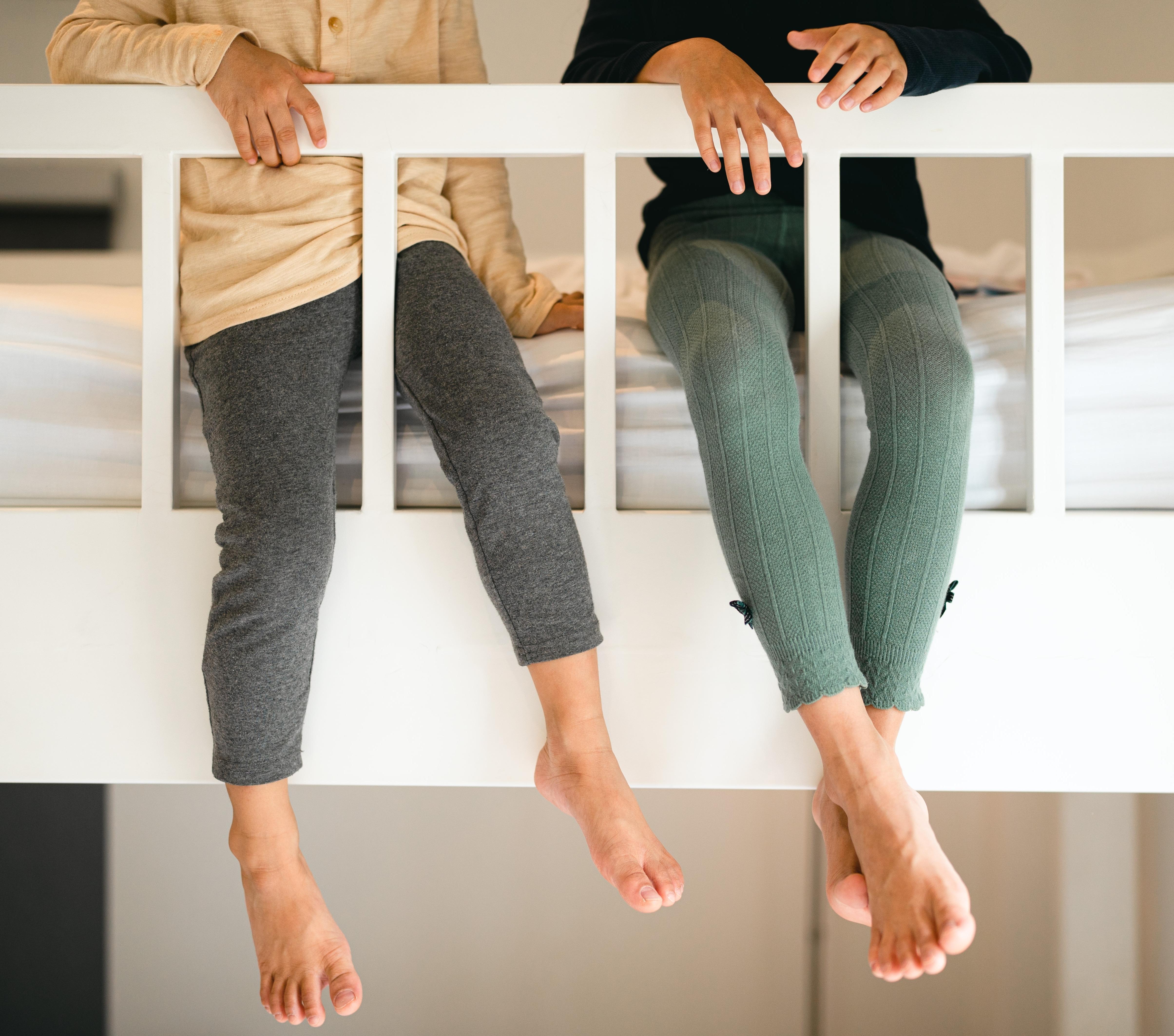 Enfants assis derrière la rambarde sécurisée d’un lit superposé, mettant en avant les mesures de sécurité du logement.