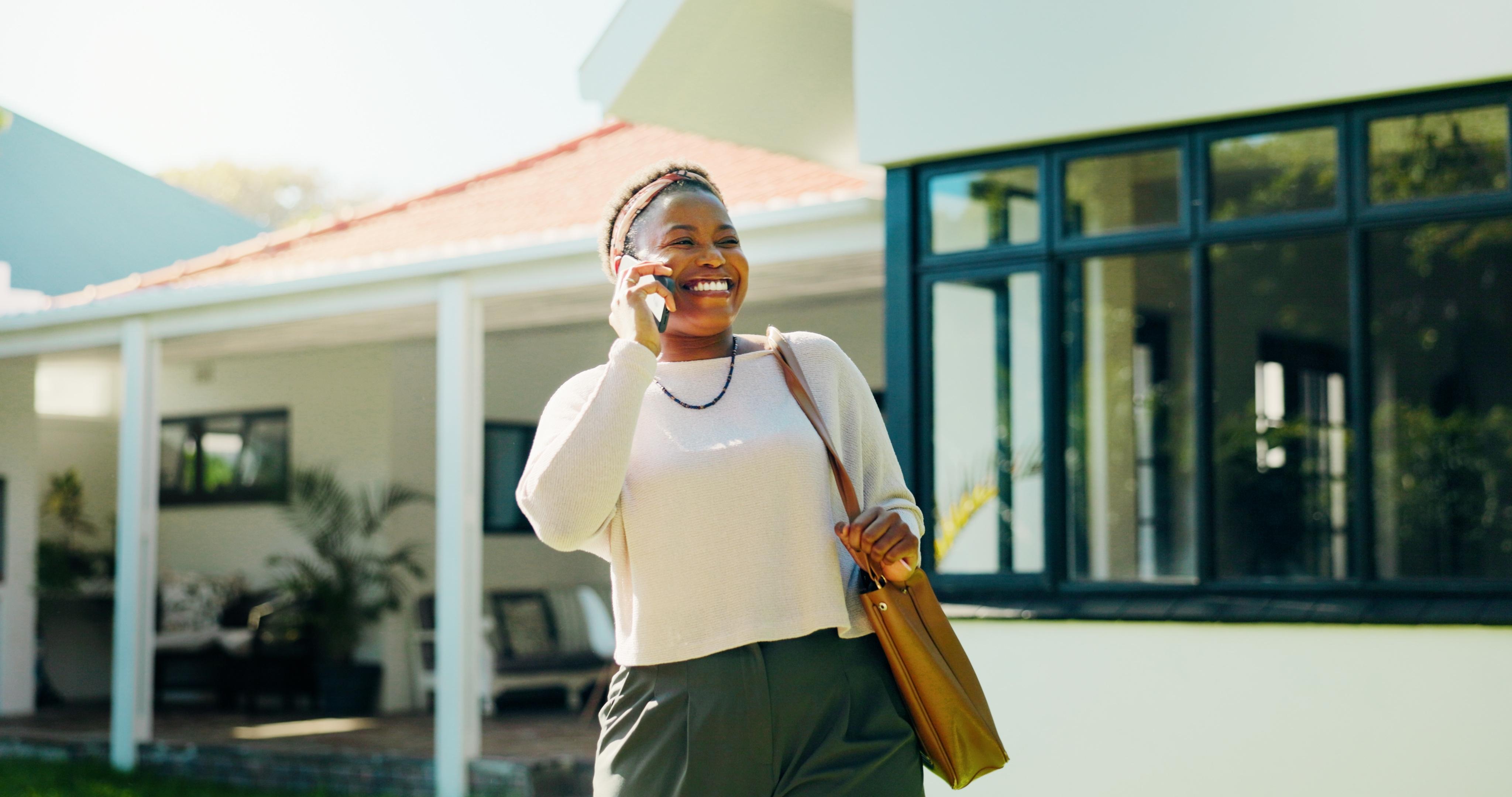 Smiling homeowner talking on the phone in front of her holiday property.