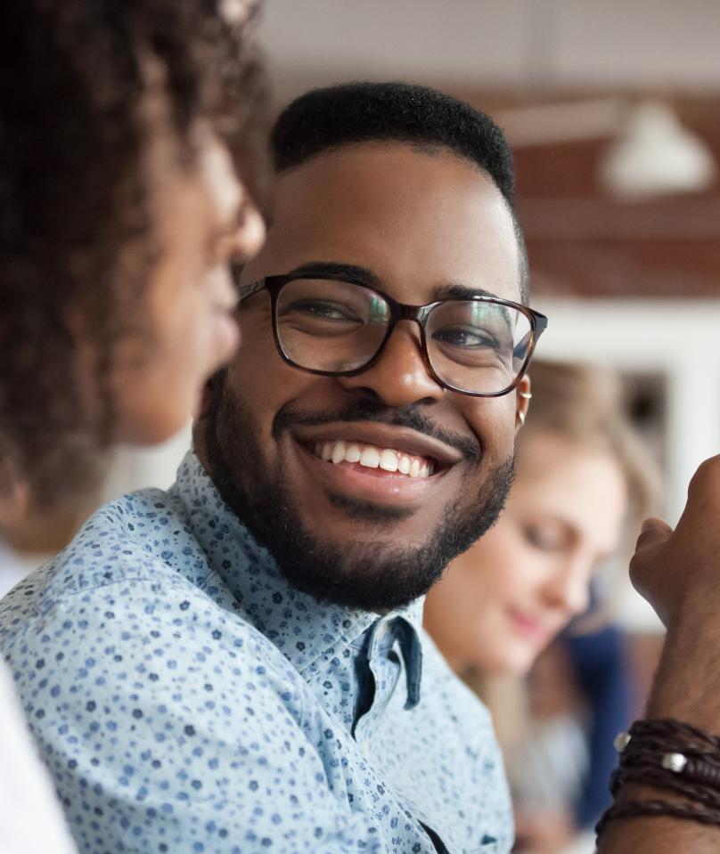 Un empleado feliz sonríe durante una conversación, lo que representa a los socios de prestaciones para los empleados.
